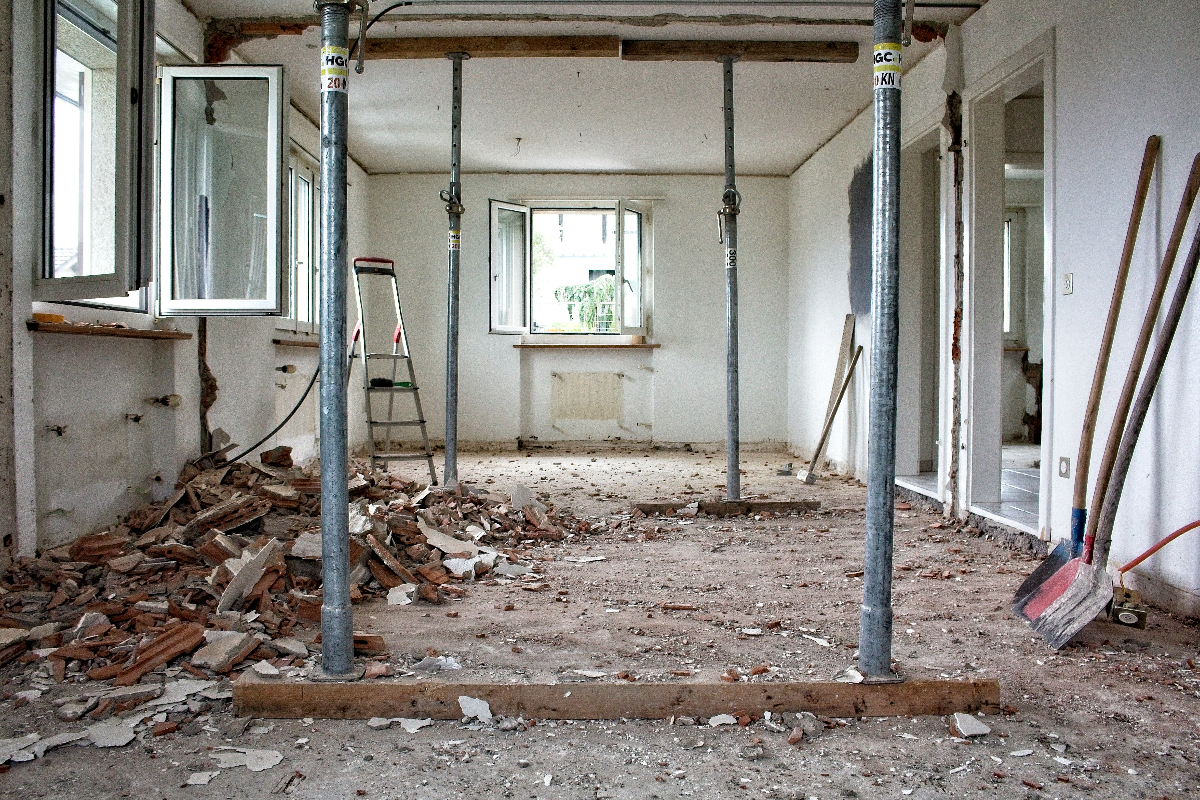 Sanierungsbedürftiger Raum mit beschädigter Decke, abblätternder Tapete und unebenem Holzboden, bereit für eine Gebäudesanierung.